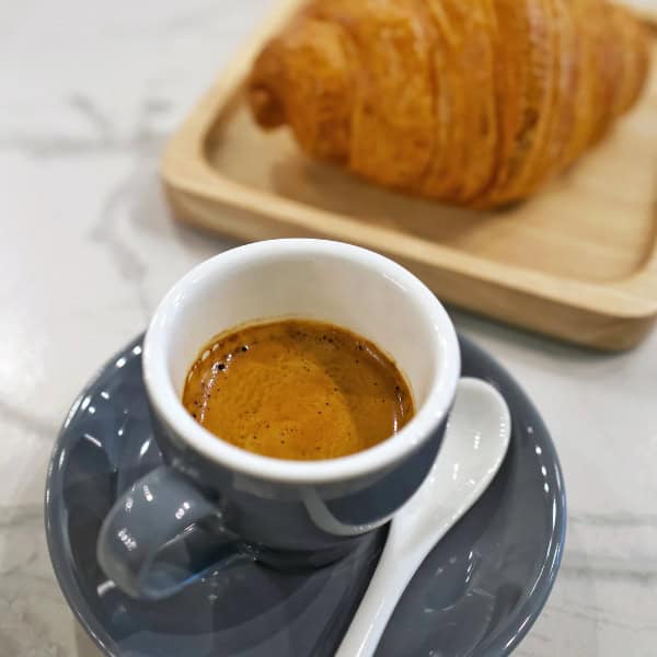 A cup of coffee and croissant at The Plus Coffee Joint